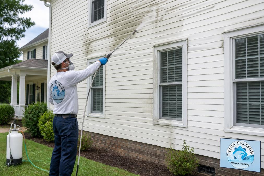 Technician using a soft wash wand on painted wood siding to determine if is soft washing safe for painted wood