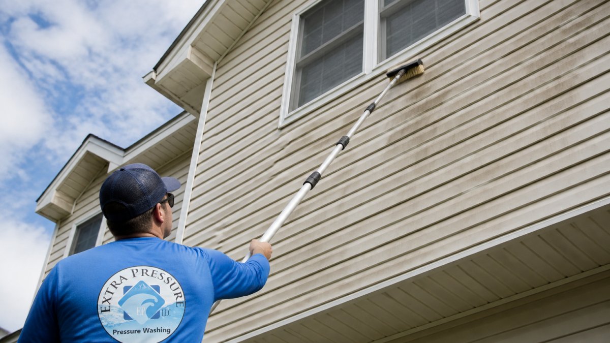 Diagram showing the process of cleaning second story siding using a telescoping pole and brush from the ground.